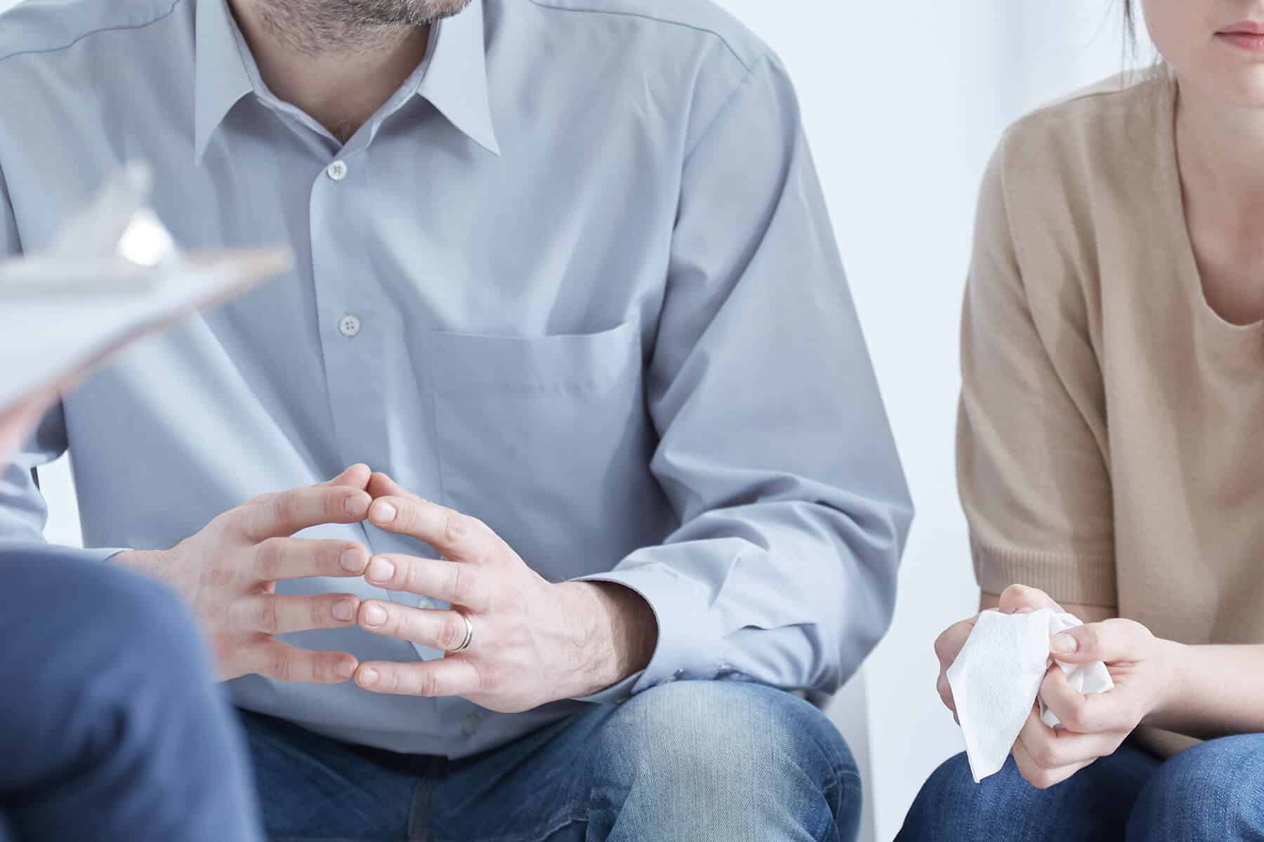 A man and woman sitting in a room, talking about their marriage relationship, while a lawyer is listening and taking notes.